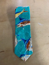 Load image into Gallery viewer, A fabric necktie featuring a repeating print of marlin fish on a bright turquoise background, laid flat on a light wood surface.
