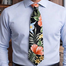 Load image into Gallery viewer, A man wearing a light blue pinstriped dress shirt and a black necktie with a vibrant tropical floral print featuring orange, yellow, and blue flowers with green leaves.

