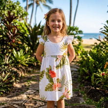 Load image into Gallery viewer, Young girl in a floral dress standing on a path with greenery and a beach in the background
